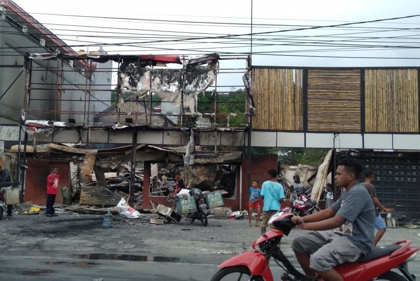Warga membersihkan puing sisa kerusuhan di salah satu gedung yang terbakar di Manokwari, Papua Barat, Selasa (20/8/2019).