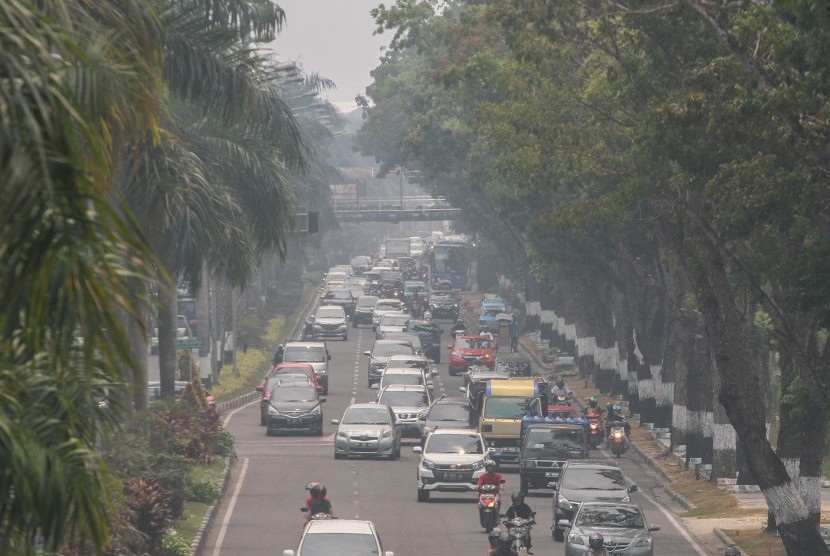 Pengendara kendaraan bermotor melintas di Jalan Sudirman ketika kabut asap tipis dampak dari kebakaran hutan dan lahan masih menyelimuti Kota Pekanbaru, Riau, Kamis (22/8/2019).