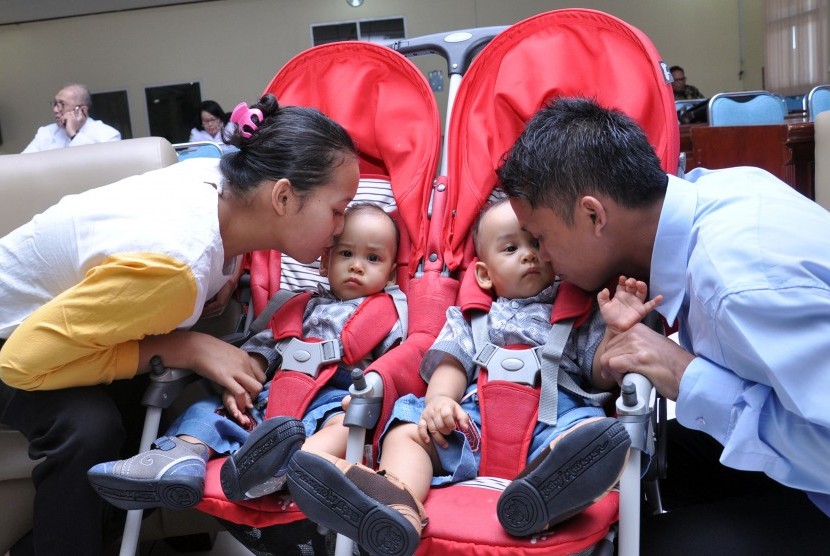 Orang tua bayi kembar siam Juliadi Silitonga (kanan) dan Nurida Sihombing (kiri) mencium anaknya sebelum dibawa pulang dari di RSUP H Adam Malik Medan, Sumatera Utara, Senin (26/8/2019).