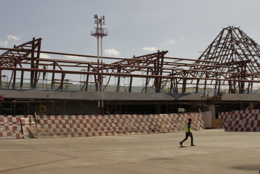 Seorang pria berjalan di depan terminal Bandara El Tari Kupang yang sedang dikerjakan oleh sejumlah pekerja. 