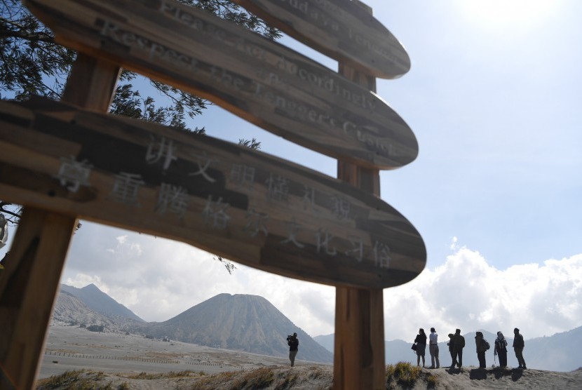 Pengunjung mengamati Gunung Bromo di samping papan rambu tiga bahasa di kawasan Gunung Bromo, Probolinggo, Jawa Timur. 