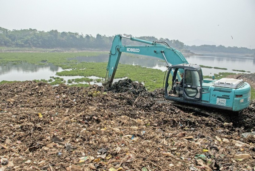 Petugas mengoperasikan alat berat untuk mengeruk sampah plastik dan sampah tanaman Eceng pada bantaran Sungai Citarum di kawasan Cihampelas, Kabupaten Bandung Barat, Jawa Barat, Kamis (29/8/2019).