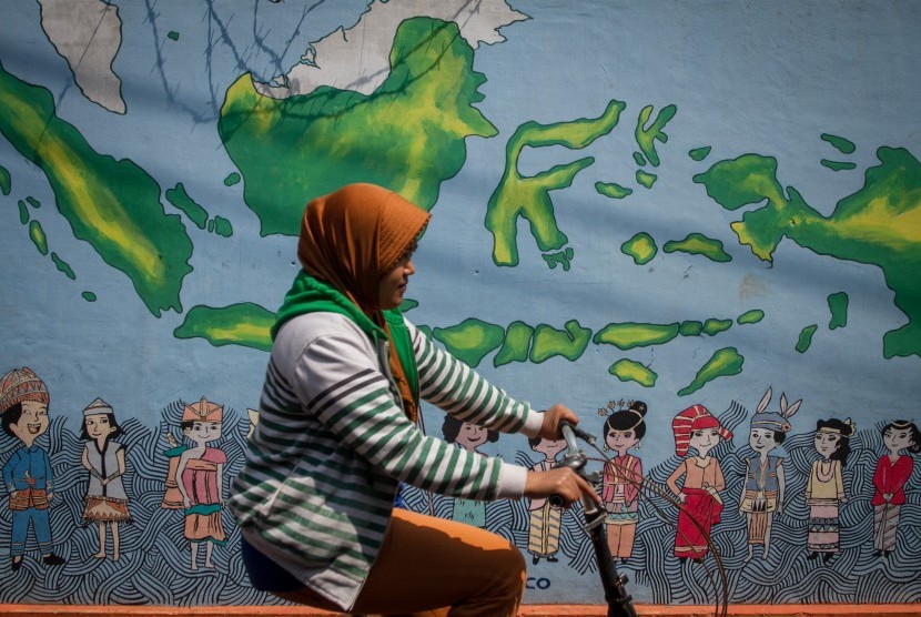 Warga melintas di depan mural bertema kebinekaan dengan gambar suku-suki di Indonesia di kampung Gremet, Manahan, Solo, Jawa Tengah, Kamis (29/8/2019).