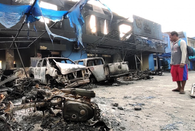 Seorang warga mengamati Kantor Bea Cukai Papua serta sejumlah mobil yang terbakar saat berlangsungnya aksi unjuk rasa di Jayapura, Papua, Jumat (30/8/2019). 