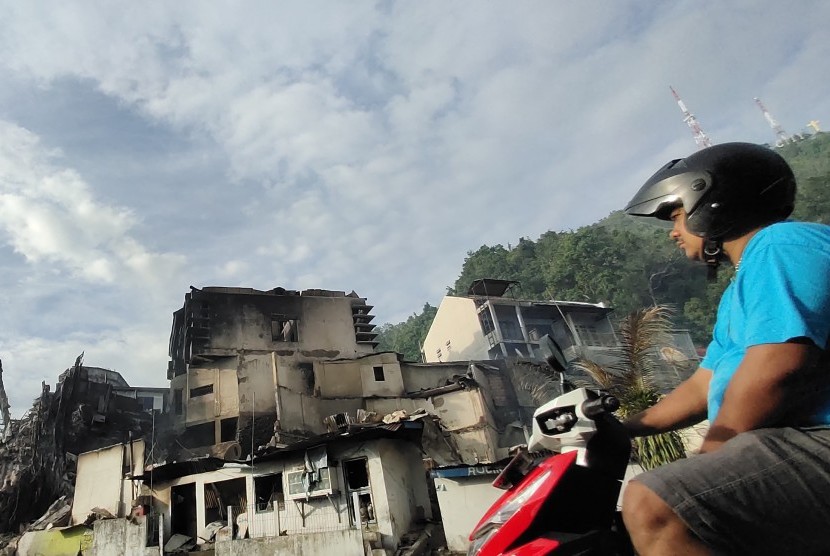 Seorang warga melintasi puing bangunan yang terbakar seusai aksi unjuk rasa di Jayapura, Papua, Jumat (30/8/2019).