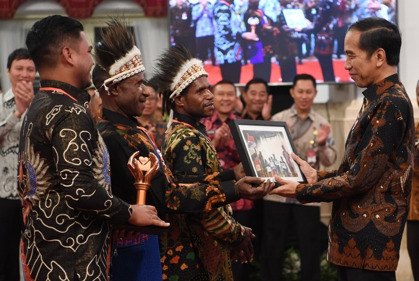 Presiden Joko Widodo (kanan) menerima foto dari peserta pemenang kategori khusus pada Festival Gapura Cinta Negeri dari Nduga di Istana Negara Jakarta, Senin (2/9/2019). 