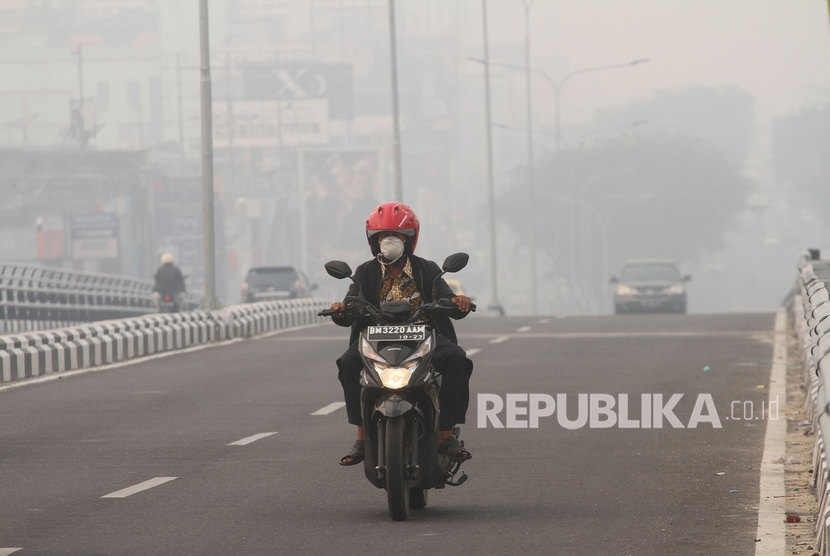 Pengendara sepeda motor menembus kabut asap pekat dampak dari kebakaran hutan dan lahan yang menyelimuti Kota Pekanbaru, Riau, Senin (9/9/2019) pagi.