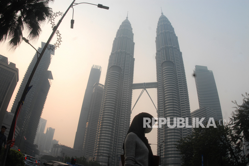 Warga beraktivitas dengan mengenakan masker di dekat menara kembar Petronas, Kuala Lumpur, Malaysia, Selasa (10/9/2019).