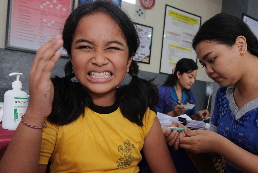 Petugas Dinas Kesehatan Kota Denpasar menyuntikkan vaksin kanker serviks kepada seorang siswi saat vaksinasi di SD Saraswati 6 Denpasar, Bali, Selasa (10/9/2019).