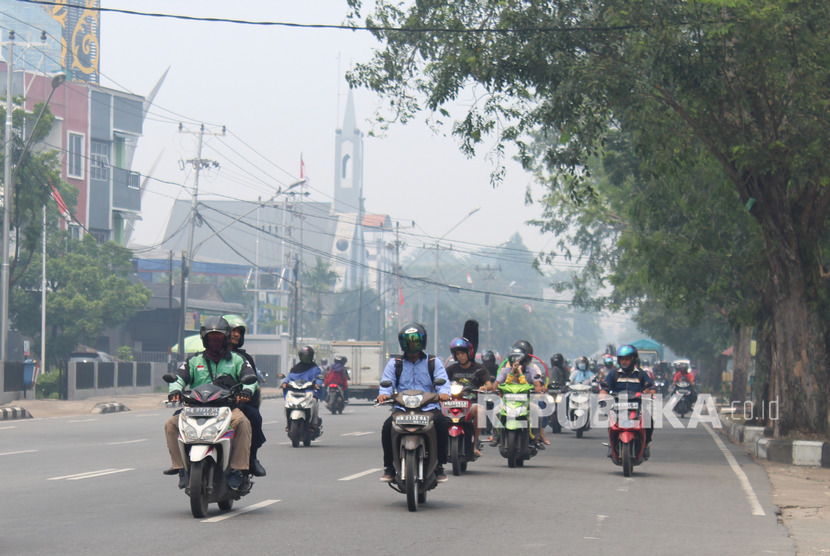 Sejumlah pengendara motor melintasi jalan yang diselimuti kabut asap di Pontianak, Kalimantan Barat, Selasa (10/9/2019).