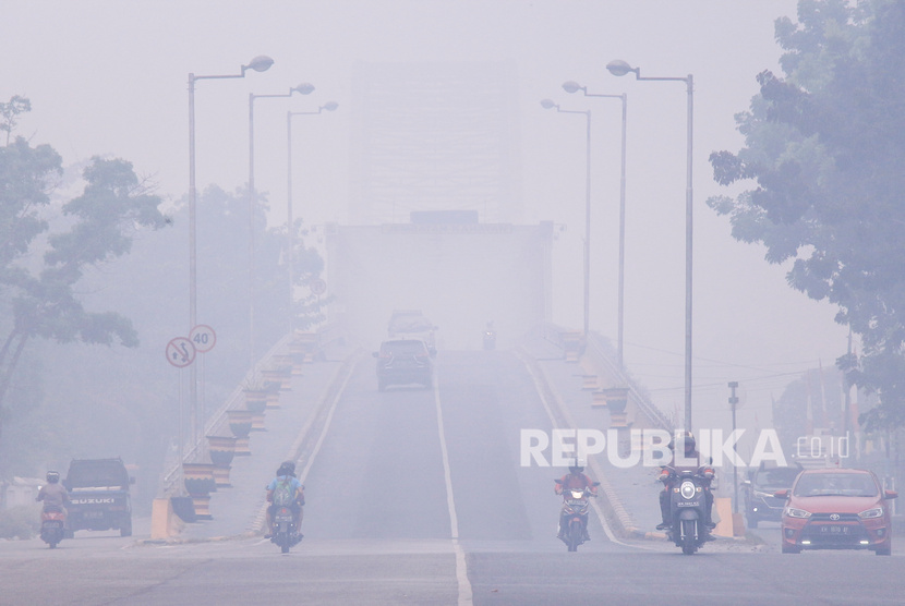 Pengendara melintas di Jembatan Kahayan yang diselimuti kabut asap di Palangka Raya, Kalimantan Tengah, Ahad (15/9/2019).