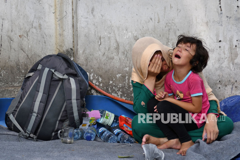 Seorang anak pencari suaka menangis di pangkuan ibunya di trotoar dekat kantor Komisioner Tinggi PBB untuk Pengungsi (UNHCR), Jalan Kebon Sirih, Jakarta Pusat, Selasa (17/9/2019). 