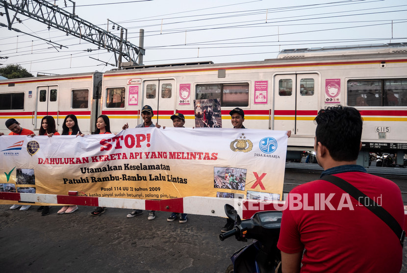 Petugas KAI Daop 1 Jakarta membentangkan spanduk dan poster saat melakukan sosialisasi keselamatan di perlintasan kereta di kawasan Bukit Duri, Manggarai, Jakarta, Selasa (17/9/2019).