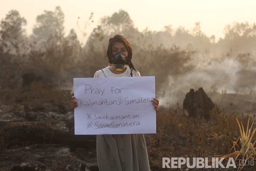 Warga berpose membawa poster bertuliskan keprihatinan kebakaran hutan dan lahan di kawasan Landasan Ulin, Banjarbaru, Kalimantan Selatan, Kamis (19/9/2019). 