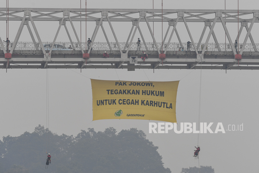 Aktivis lingkungan Greenpeace Indonesia dan Save Our Borneo melakukan aksi pembentangan spanduk raksasa di bawah Jembatan Kahayan, Palangka Raya, Kalimantan Tengah, Ahad (22/9/2019).