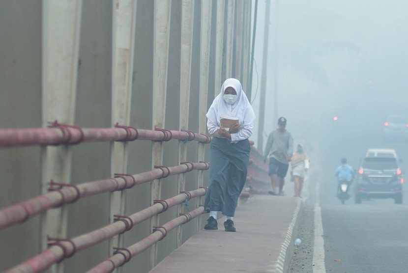 Seorang siswa mengenakan masker saat berjalan menyusuri jembatan, di Palembang, Sumatera Selatan, Senin (23/9/2019). 