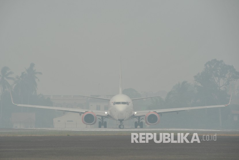 Sebuah pesawat udara bersiap lepas landas di Bandara Sultan Thaha yang diselimuti kabut asap karhutla, Jambi, Senin (23/9/2019). 