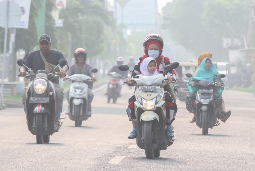 Warga tidak memakai masker mengabaikan kesehatan melewati polusi asap yang menyelimuti jalan Pase, Kota Lhokseumawe, Aceh, Selasa (24/9/2019). 