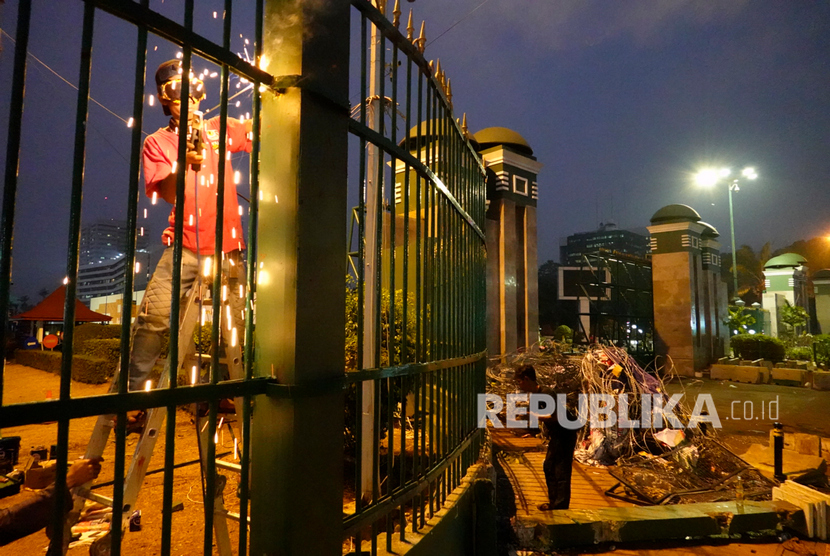 Pekerja memperbaiki pagar pascaaksi unjuk rasa mahasiswa menolak Undang-Undang KPK hasil revisi dan rencana pengesahan Rancangan Kitab Undang-Undang Hukum Pidana (RKUHP) di Gedung DPR/MPR, Senayan, Jakarta, Rabu (25/9/2019).