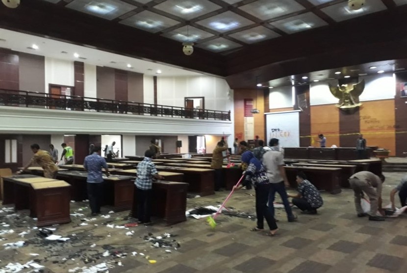 Petugas membersihkan serpihan pecahan kaca di ruang sidang utama DPRD Sumbar usai digeruduk mahasiswa yang melakukan aksi pada Rabu (26/9).