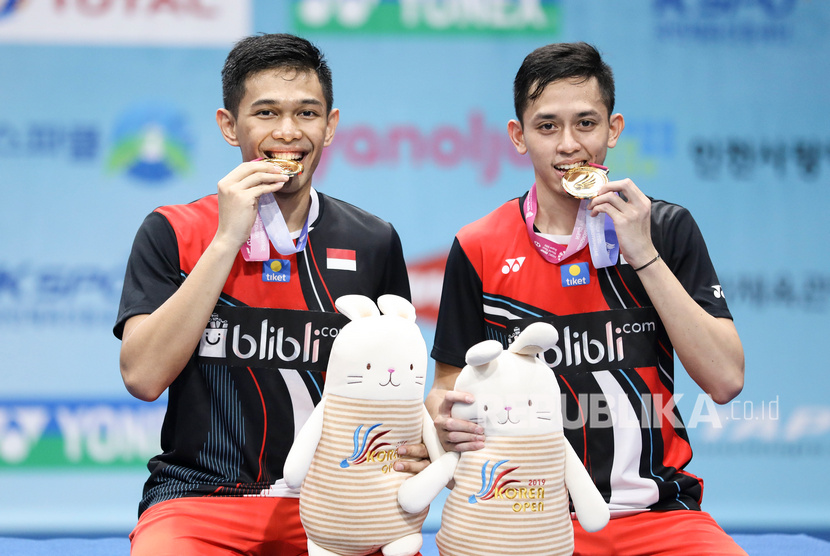 Ganda putra Indonesia Fajar Alfian (kiri) dan Muhammad Rian Ardianto menggigit medali di atas podium seusai keluar sebagai juara Korea Open sebelum pandemi Covid-19 merebak di dunia.