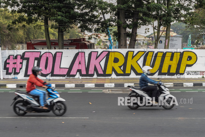 Sejumlah pengendara motor melintasi mural kritik sosial 'Tolak RUU KUHP' di Rawamangun, Jakarta Timur, Ahad (29/9/2019).