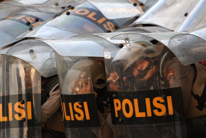 Sejumlah polisi berlindung dengan tameng dari lemparan batu saat kericuhan dalam unjuk rasa di Jalan Gatot Subroto, dekat kompleks Parlemen, Jakarta, Senin (30/9/2019).