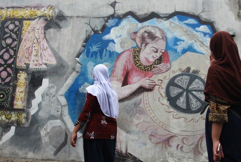 Dua orang siswi mengamati mural bergambar perajin batik yang ada di Kampung Batik Tangerang, Larangan, Tangerang, Banten, Rabu (2/10/2019). 