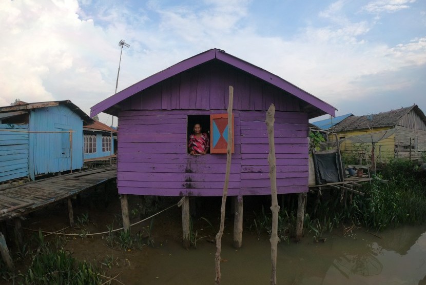 Seorang ibu melihat keluar dari jendela rumahnya yang sudah dicat warna ungu di perkampungan nelayan (ilustrasi)