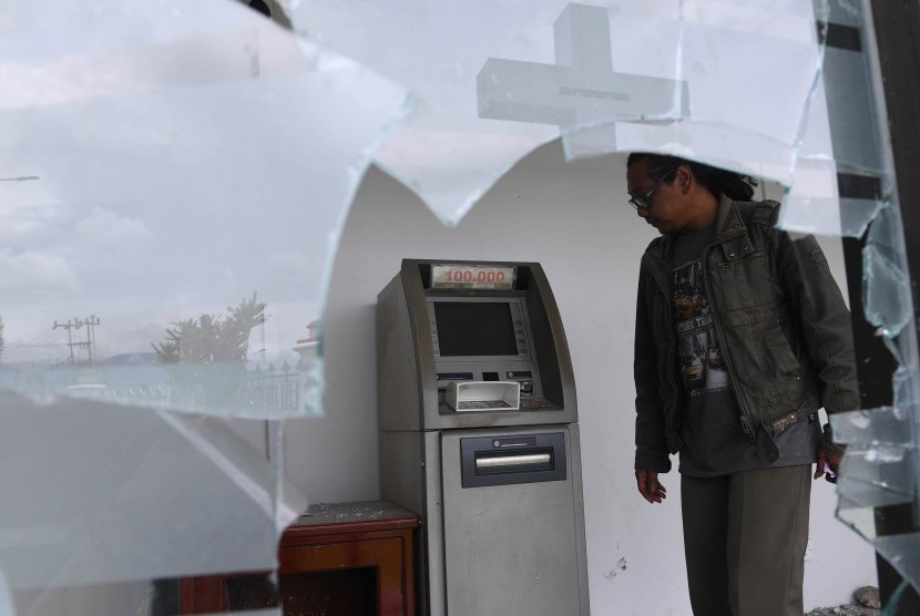 Seorang warga mengamati mesin Anjungan Tunai Mandiri (ATM) bersama yang rusak di kompleks Kantor Bupati Jayawijaya, Wamena, Papua, Rabu (9/10/2019). 