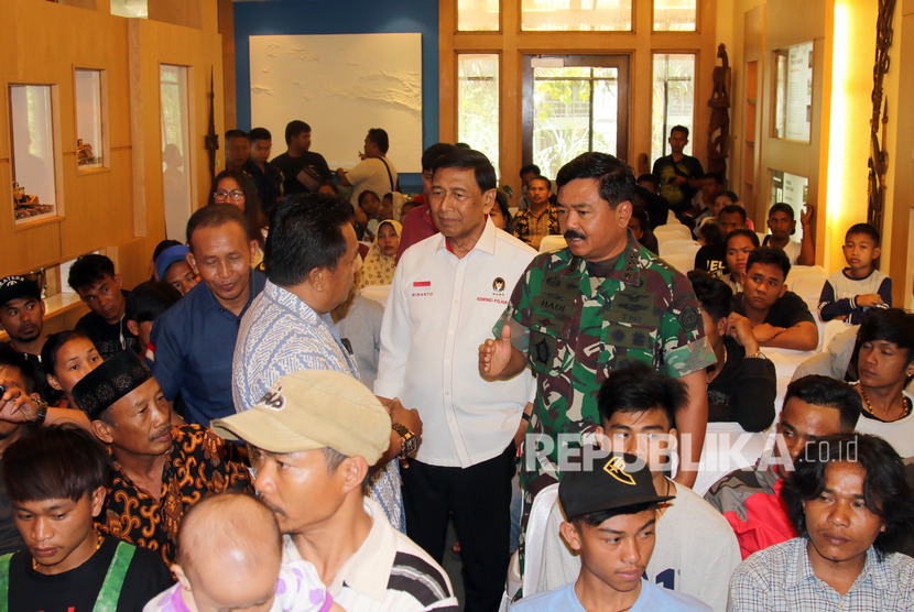 Menko Polhukam Wiranto (tengah) didampingi Panglima TNI Marsekal Hadi Tjahjanto (kanan) berbincang dengan pengungsi Wamena dan Ilaga di Timika, Mimika, Papua, Rabu (9/10/2019).