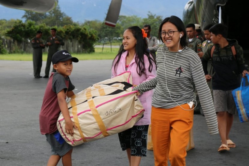 Sejumlah pengungsi mengangkat barang bawaannya ketika tiba dengan menumpang pesawat Hercules TNI AU di Bandar Udara Wamena, Papua, Rabu (9/10/2018).