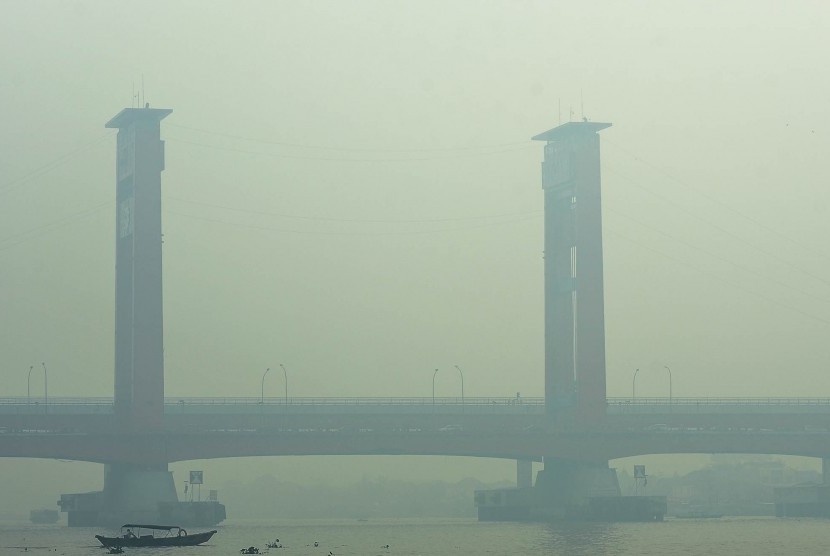 Warga beraktivitas di perairan Sungai Musi yang tertutup kabut asap di Palembang, Sumatra Selatan. 