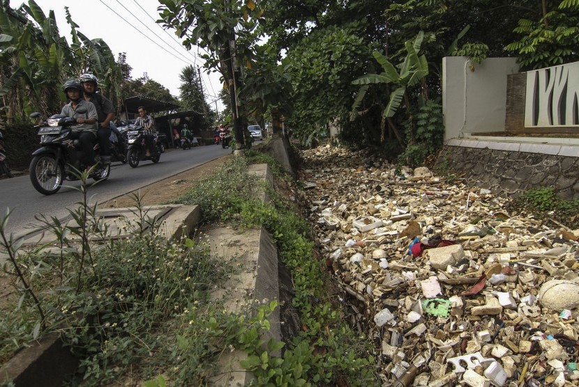 Pengendara melintas di samping aliran Kali Krukut yang dipenuhi tumpukkan sampah di Depok, Jawa Barat, Jumat (11/10/2019). 