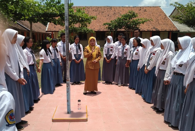 Guru mengajarkan teori kulminasi matahari di luar kelas saat mata pelajaran Fisika.