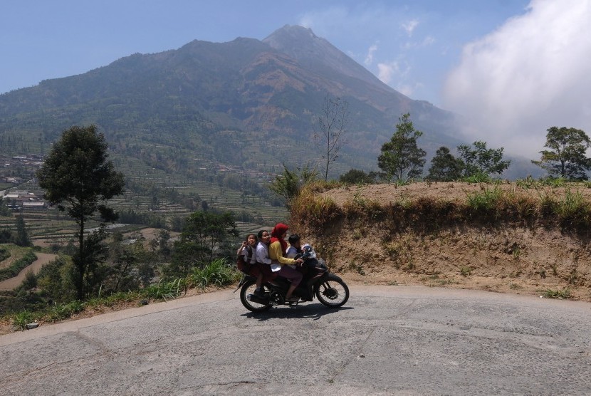 Warga melintas dengan latar belangkang Gunung Merapi di kawasan Selo, Boyolali, Jawa Tengah, Selasa (15/10/2019). 