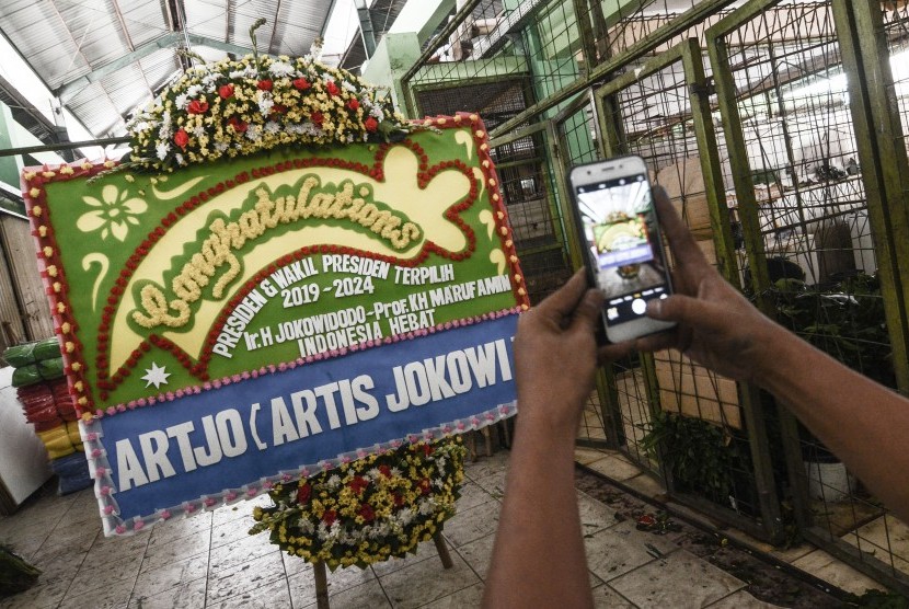 Pedagang mengabadikan karangan bunga ucapan selamat kepada Presiden terpilih Joko Widodo dan Wakil Presiden Ma’ruf Amin di Pasar Rawa Belong, Jakarta Barat, Sabtu (19/10/2019). 