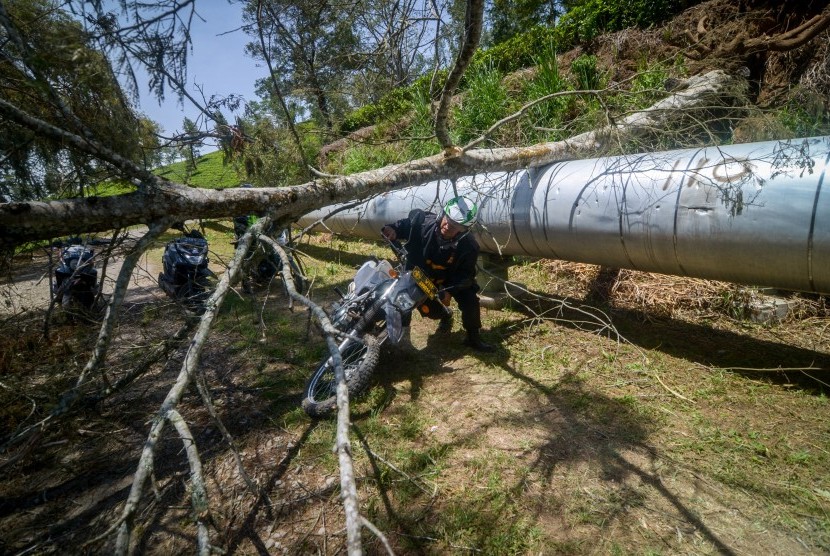 Seorang anggota kepolisian berusaha melewati pohon tumbang akibat bencana angin ribut yang terjadi di Pangalengan, Kabupaten Bandung, Jawa Barat, Senin (21/10/2019).