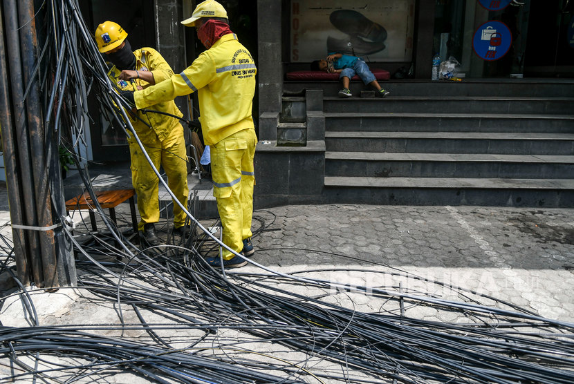 Pekerja Dinas Bina Marga Provinsi DKI Jakarta memotong kabel utilitas yang semrawut di kawasan Kemang, Jakarta, Selasa (22/10/2019).