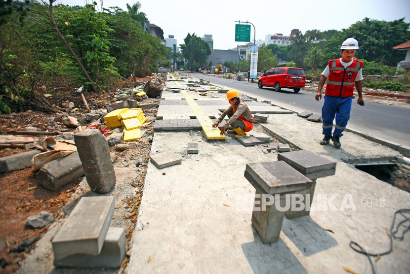 Pekerja melakukan pengerjaan pelebaran trotoar di kawasan Kemang, Jakarta Selatan.