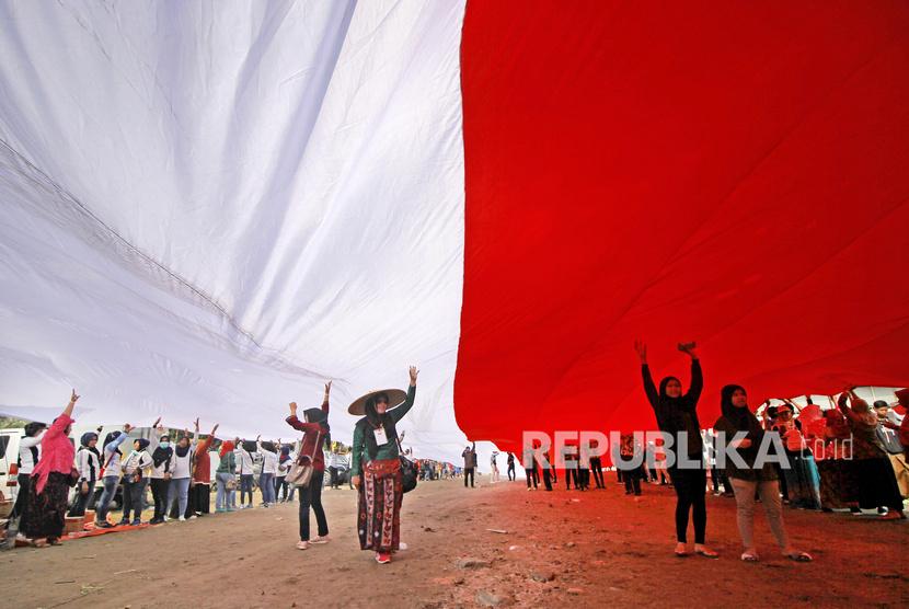 Warga membentangkan bendera Merah Putih saat memperingati Hari Sumpah Pemuda di kampung nelayan Greges, Surabaya, Jawa Timur, Ahad (27/10/2019). 