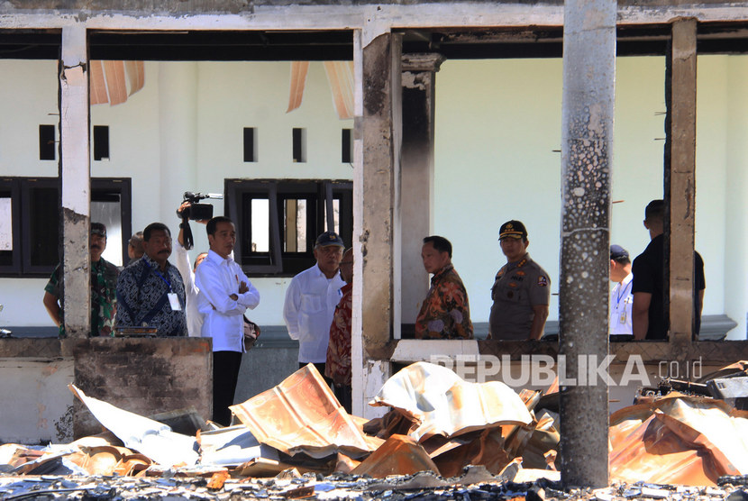 Presiden Joko Widodo (ketiga kiri) didampingi Mendagri Tito Karnavian (keempat kanan), Menteri PUPR Basuki Hadimuljono (keempat kiri), Panglima TNI Marsekal TNI Hadi Tjahjanto (kiri), Gubernur Papua Lukas Enembe (kelima kiri) dan Bupati Jayawijaya John Richard Banua (kedua kiri) mengamati bangunan yang terbakar saat kerusuhan lalu di Kantor Bupati Jayawijaya, Wamena, Papua, Senin (28/10/2019). 