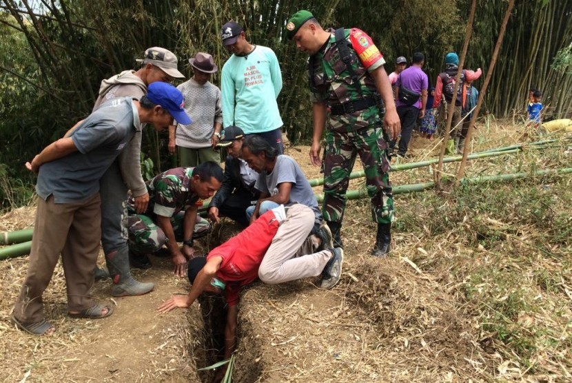 Warga memindahkan makam lantaran terjadi pergerakan tanah di Kampung Sukasari, Desa Mekarsari, Kecamatan Cikajang, Kabupaten Garut, Rab (30/10). 