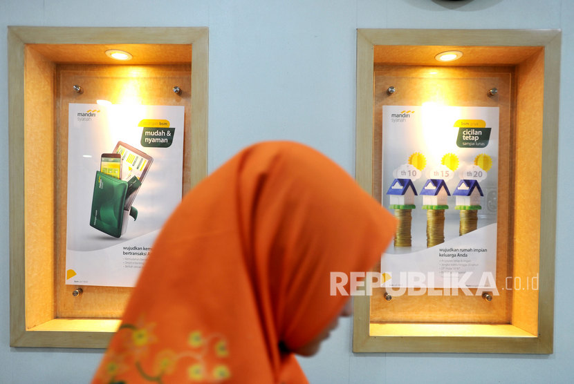 Pegawai Bank Syariah Mandiri (Mandiri Syariah) melintas di dekat poster tentang layanan di Kantor Cabang Jakarta Menteng, Jakarta, (ilustrasi).