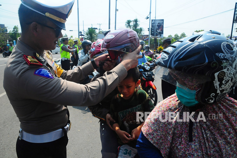 (ILUSTRASI) Polisi memakaikan helm yang dibagikan secara gratis saat operasi. 