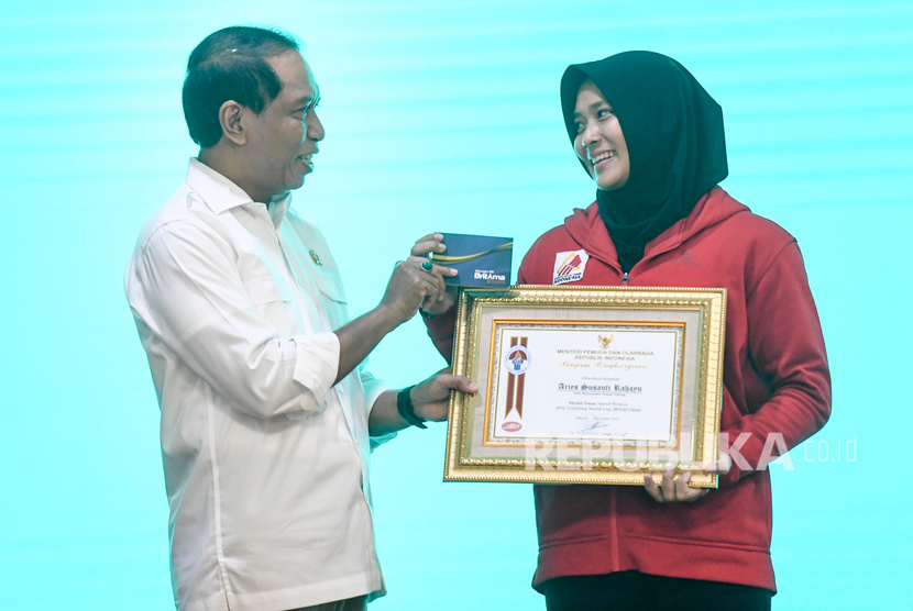 Menpora Zainudin Amali (kiri) menyerahkan buku tabungan kepada atlet panjat tebing putri Indonesia Aries Susanti Rahayu saat penyerahan bonus atlet juara dunia di Jakarta, Selasa (5/11/2019).