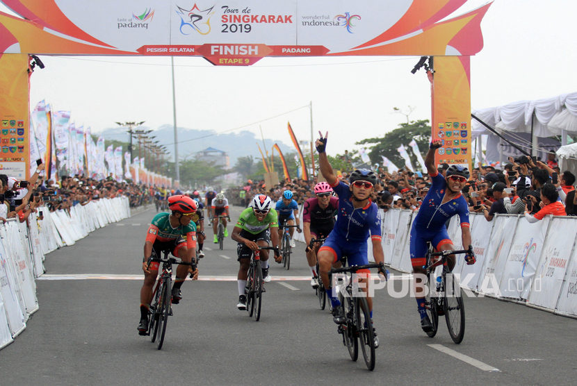 Pebalap Azman Muhammad Zawawi (tengah) mengangkat tangannya setelah memasuki garis finis saat mengikuti Tour De Singkarak 2019 etape kesembilan di Padang, Sumatera Barat, Ahad (10/11/2019).