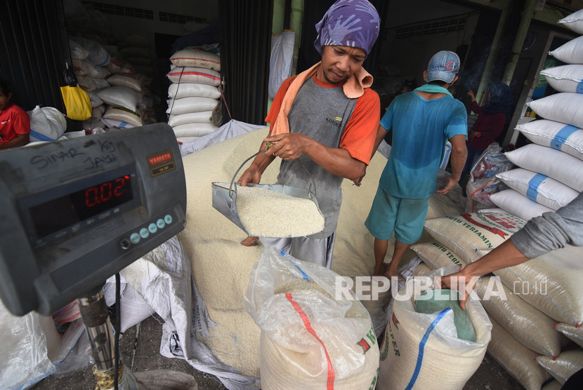 Pekerja mengemas beras ke dalam karung di Pasar Induk Beras Cipinang, Jakarta, Senin (11/11/2019).