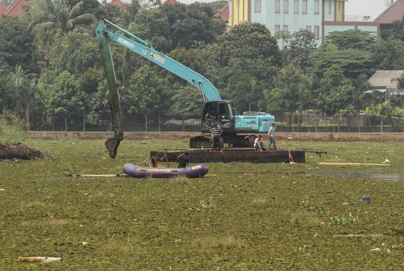 Petugas membersihkan Situ Sawangan dari tanaman Azolla pinnata dengan alat berat di Sawangan, Depok, Jawa Barat, Jumat (22/11/2019).