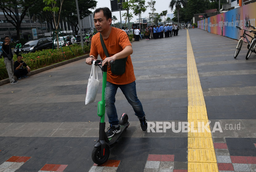 Pengendara skuter listrik melintas di trotoar Jalan Sudirman, Jakarta, Jumat (22/11/2019).